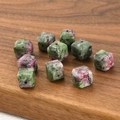 Macro detail of cube-shaped natural anyolite stone spacer beads on a wooden tray - Unakite Cube