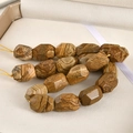 Close-up of faceted barrel-shaped natural jasper beads with earthy wood-like textures - Jasper / 1 Piece