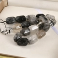 Macro shot of faceted black rutilated quartz tube beads on a white display tray - Black Rutilated Quartz / 1 Piece