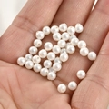Close-up of white round faux pearls held in hand for DIY jewelry making material - 4mm White Pearl Bead (Approx 4.2mm)