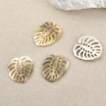 Macro detail of hand-carved shell leaf pendants with natural iridescent luster for jewelry - Small Monstera Style