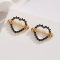 Close-up of golden stainless steel heart nipple rings with deep blue zircon pave detail - Gold Blue