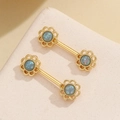 Close-up of gold-plated sunflower body rings with blue opal stones on stone base - Blue