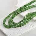 Macro shot of 6mm green sugar cube glass beads with cat eye effect and silver spacers - One Strand Approx 55 Beads / Emerald Green