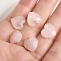 Hand holding five faceted pink quartz heart pendants with pre-drilled holes for DIY jewelry - Rose Quartz Heart