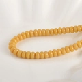 Vista macro de cuentas de vidrio amarillas en plato de cerámica para joyería DIY - Cuenta Ábaco Amarillo Proteína