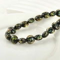 Macro detail of oval black glass beads with colorful foil inserts for DIY jewelry making - Amber Yellow Foil