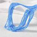 Detailaufnahme von 2mm blauen Katzenaugen-Perlen auf einem weißen minimalistischen Ständer - Seebleuer Katzenaugen-Stil