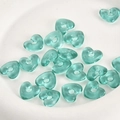 Makro-Detail von blauen, durchscheinenden herzförmigen Glasperlen für DIY-Schmuck - Pfauengrün Herz