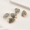 Vue détaillée de cinq pendentifs cœurs en pierre naturelle grise avec bordure dorée à l'or - Cœur Labradorite