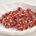 Nahaufnahme handgefertigter roter Lampwork-Glasperlen mit bunten Punkten in einer Schale - Rot
