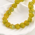 Macro detail of yellow handmade glass rose bead with gradient texture in shell tray - Yellow