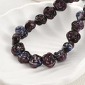 Macro detail of handmade purple glass rose beads with blue swirl gradient texture - Grape Purple