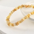 Primer plano de cuentas de concha natural amarillas y crema en un cuenco blanco - Amarillo