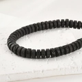Nahaufnahme von 4x8mm schwarzen Lavasteinperlen mit poröser Textur auf Steinständer - 4*8mm / Schwarz