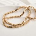 Makroaufnahme vergoldeter Lavastein-Würfelperlen für DIY-Schmuck auf weißem Keramiktablett - KC Gold (3mm)