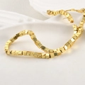 Makroaufnahme von vergoldeten quadratischen Vulkansteinperlen auf einem weißen Keramikteller - Imitationsgold (4mm)