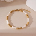 Gold plated stainless steel beaded bracelet with cross and star charms on beige surface - Gold Bone