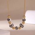 Detail of 18K gold plated chain with blue and white porcelain beads and gold metallic spheres - Black