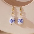 Macro shot of blue and white floral porcelain earrings with gold hooks and pearl accents - Oval Style (Model D)