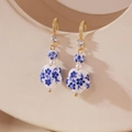 Detailed close-up of blue and white porcelain earrings with gold hooks and pearl accents - Flower Style (Model C)
