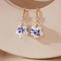 Detail of star-shaped blue and white porcelain earrings with gold hooks and tiny crystals - Star Style (Model A)