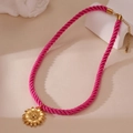 Detail of the golden sunflower pendant on a vibrant pink woven cord necklace - Flower