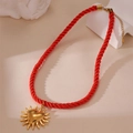Detailed shot of red woven rope necklace with golden heart-shaped sunburst pendant - Heart Sun