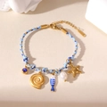 Nautical braided rope bracelet with gold starfish, pearl and fish charms for women - Blue