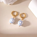 Detailed view of vintage blue and white tulip porcelain beads on golden hoop earrings - White