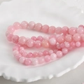 Macro detail of 8mm natural Persian jade round beads in peach pink on white ceramic tray - Peach Pink 8mm (Approx. 46 Beads)