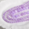 Macro detail of 8mm lavender Persian jade round beads on a decorative white porcelain plate - Lavender Purple 8mm (Approx. 46 Beads)