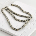 Detailed view of natural Dalmatian Jasper flat beads on a textured plaster display board - 6# Abacus Bead Style / 2x4mm (160 Pieces/Pack) / Dalmatian Jasper
