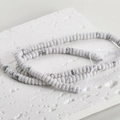 Close-up of natural white turquoise disc beads with grey marble texture on a stone plate - 18# Abacus Bead Style / 2x4mm (160 Pieces/Pack) / Howlite