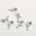 Macro shot of silver rose pendants with inlaid zircons and loops for jewelry making - White Gold Rose Style
