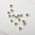 Macro view of 14k gold-plated heart charms with blue zircon and delicate wavy edges - Lake Blue Zirconia
