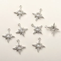 Macro view of 8 pieces of silver star charms with sparkling cubic zirconia for DIY jewelry - Starburst Design / White K Starburst