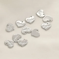 Macro shot of 11 heart-shaped silver metal pendants with Handmade engraving for DIY jewelry - Silver Heart Style
