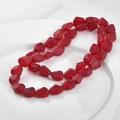 Dettaglio di perle di cristallo rosso opaco irregolari su un vassoio di ceramica bianca - Rosso Satinato Irregolare (16#)