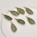 Macro detail of seven faceted green stone teardrop pendants with gold textured borders - Green Strawberry Quartz (No. 4 Irregular Shape)