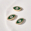 Detail von grünen Evil-Eye-Perlen mit goldenen Wimpern auf einem weißen Tablett - Augenform / 1 Stück (18.4x10.6x4.86mm) / Grün