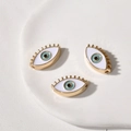 Detailansicht von drei blauen Evil Eye Anhängern mit goldenen Metallwimpern für DIY-Schmuck - Augenform / 1 Stück (18.4x10.6x4.86mm) / Weiß