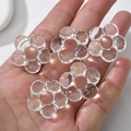 Detailed macro view of five transparent flower-shaped beads held in a hand for jewelry DIY - Flower Style (13#) / 1 Piece / Transparent White