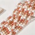 Detailed macro view of 8mm rainbow glass beads in peach and gold for DIY jewelry - Orange Red Multicolor