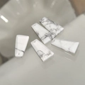 Macro shot of five trapezoid natural white stone pendants with gray veins for jewelry making - Howlite