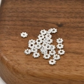 Macro view of silver plated snowflake spacer beads for DIY jewelry making on wood - 15# Style (4mm / 50 Pcs/Pack) / Silver