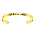 Macro shot of gold cuff bracelet with 'keep fucking going' engraving and arrow detail - C-Shape (B820) / Gold