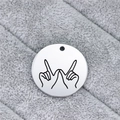 Macro shot of silver stainless steel round pendant with laser-engraved hand gesture design - Whatever Gesture (AL337)