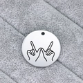 Polished round stainless steel pendant with engraved hand gesture on plush grey fabric - Gesture Pendant / Silver