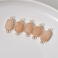 Five rectangular pale pink stone connectors with gold plated bezels on white ceramic tray - Pink Aventurine Connector